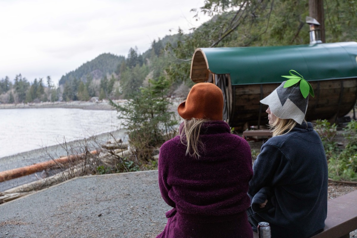 Sauna hats being worn beside a wood-fired barrel sauna